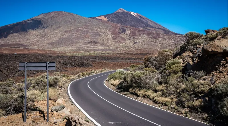 The TF-21 road curving through lava fields towards Mount Teide